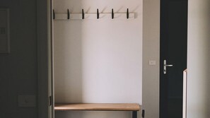 A room with a wooden bench, a coat rack, and a door.