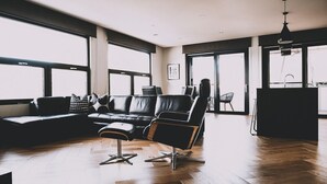 A modern living room with a leather sofa, a black chair, and a dining area with a chair and table.