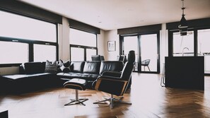 A modern living room with a leather sofa, a black chair, and a dining area with a chair and table.