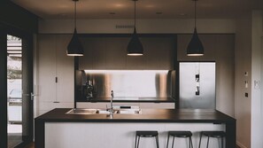 A modern kitchen with a central island, pendant lighting, and a view of the outdoors.
