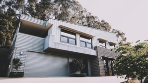 Uma casa moderna de dois andares com telhado plano, janelas amplas e garagem.