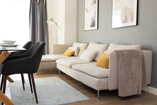 Un salon moderne comprenant un canapé, deux fauteuils, une table basse et un lampadaire.