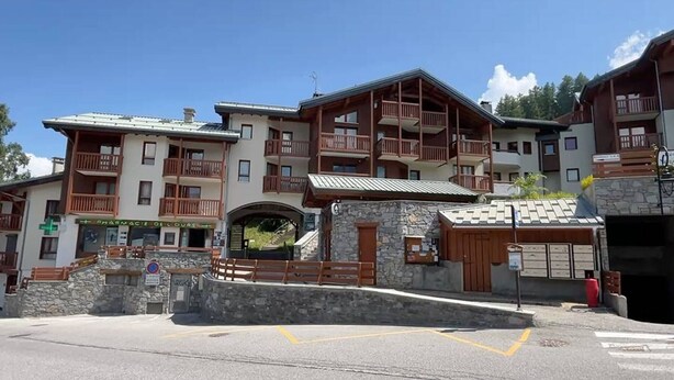 A multi-story building with balconies, a pharmacy, and a stone entrance. - Cozy apartment for 6, near slopes, includes parking (Peisey-Nancroix-Plan Peisey)