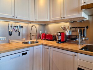 A modern kitchen with stainless steel appliances, a built-in dishwasher, and a variety of utensils and cookware.