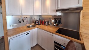 A compact kitchen with white cabinets, a stainless steel sink, and a built-in oven.