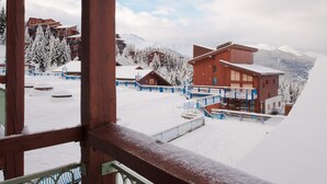A snow-covered resort with wooden buildings and a ski lift.