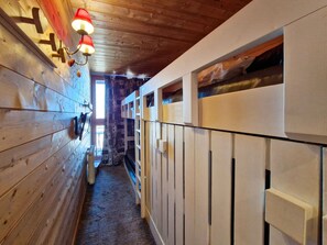 A narrow hallway with wooden walls and a ceiling, leading to a staircase.