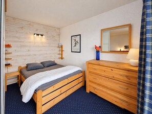 Un dormitorio con una cama de madera, un aparador, un espejo y un estante en la pared.
