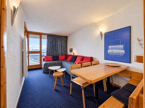 A cozy room with a wooden table, a sofa, and a view of the mountains. - Arc 1800 - 5 pers apartment, balcony, wifi (Les Arcs 1800)