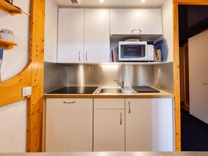 A compact kitchenette with a microwave, sink, and cabinets. - Arc 1800 - 5 pers apartment, balcony, wifi (Les Arcs 1800)
