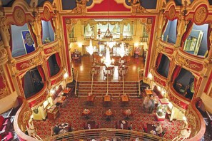 Un intérieur de théâtre somptueux, avec une scène centrale, de nombreux balcons et un lustre.