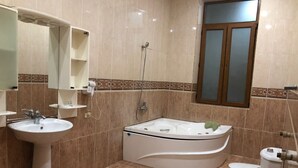 Un baño con lavamanos, bañera, inodoro y ducha.