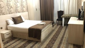 Una habitación de hotel con cama, escritorio, silla y armario.