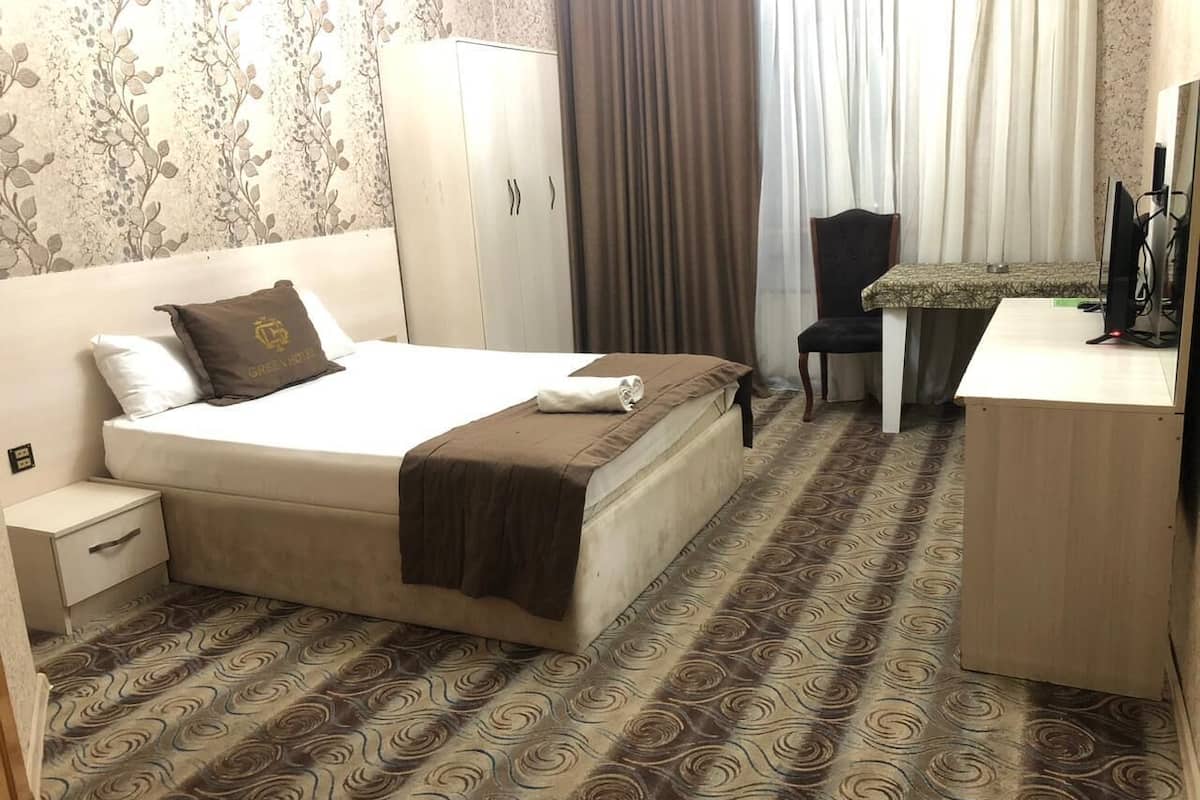 Une chambre d’hôtel avec un lit, un bureau, une chaise et une armoire.