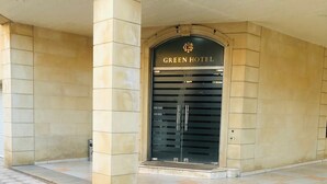 La entrada del Hotel Green, con pavimento de baldosas y fachada de piedra.