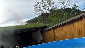 A swimming pool with clear water, a wooden deck, and a view of a building with a sloped roof. - Cazare Apuseni  Pensiune cu ciubăr (Vidra)