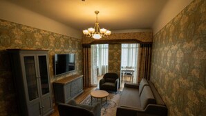 Een woonkamer met een bank, fauteuils, een televisie en een kast.