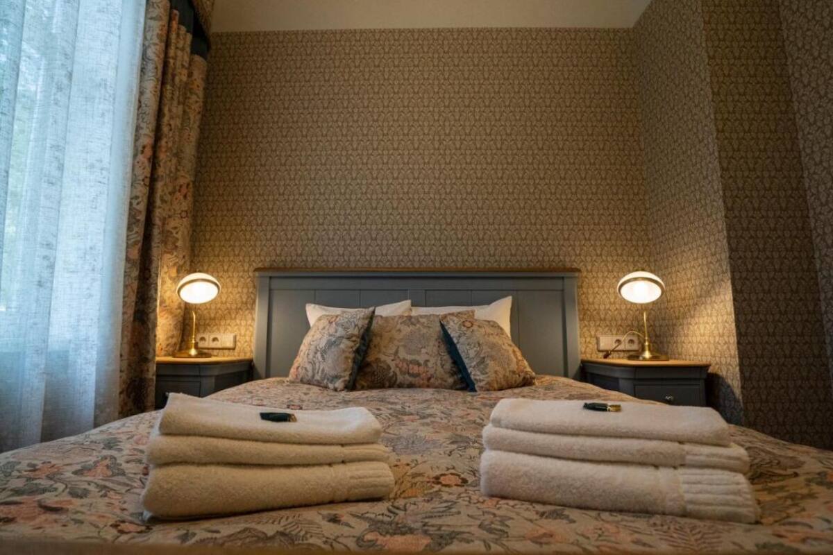 Una habitación de hotel con una cama grande, dos lámparas de noche y un papel tapiz estampado.