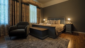 Een slaapkamer met een bed, nachtkastjes, een stoel en een vloerkleed.