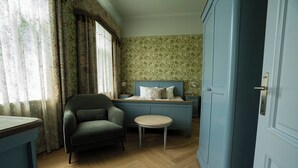 Een slaapkamer met een bed, een stoel, een klein tafeltje en een kledingkast.