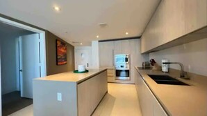 A modern kitchen with a central island, built-in oven, and stainless steel appliances. - Ocean-View Corner 1BR-1BA - 18th Floor, LYFE Resort & Residences (Hollywood)