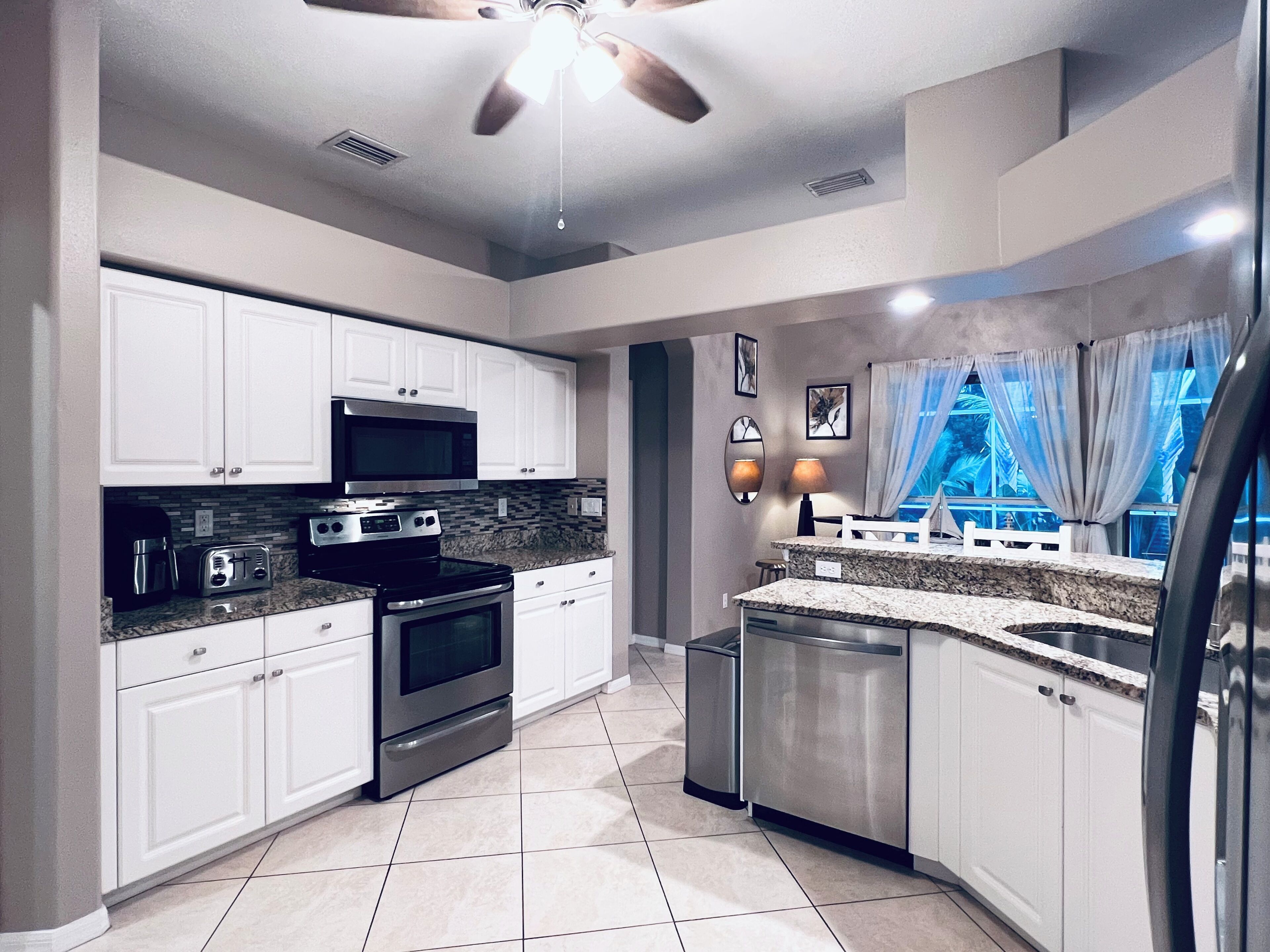 A modern kitchen with white cabinets, stainless steel appliances, and a granite countertop.