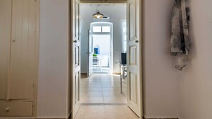 A hallway leading to a room with a door, a light fixture, and a coat hanging on the wall. - Cycladic home in Adamas, Casa Nostalgia, Greece (Milos)