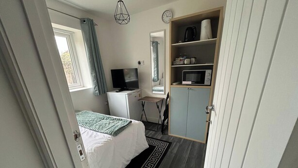 A compact bedroom with a bed, a television, a microwave, and a wardrobe. - Private Room, Sleeps 2 With Ensuite & Parking (Birmingham)