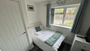 A bedroom with a bed, a window with curtains, a desk, and a radiator. - Private Room, Sleeps 2 With Ensuite & Parking (Birmingham)