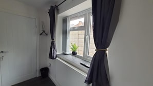 A narrow hallway with a radiator, a door, and a window with curtains. - Private Room, Sleeps 2 With Ensuite & Parking (Birmingham)