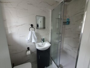 A bathroom with a white sink, a glass shower enclosure, and a marble-tiled wall. - Private Room, Sleeps 2 With Ensuite & Parking (Birmingham)