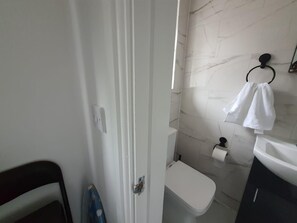 Un baño con inodoro, toallero y dispensador de papel higiénico.