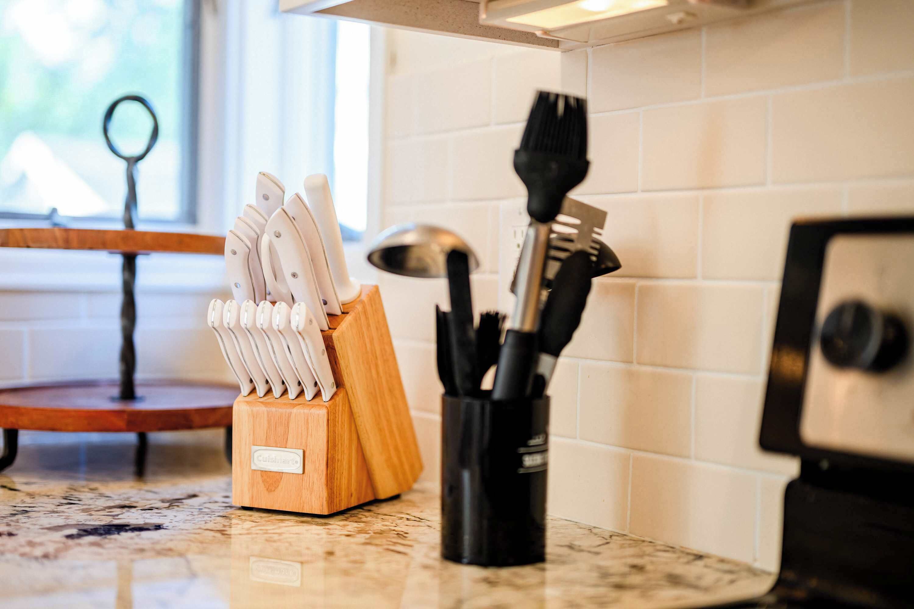 A kitchen counter with a knife block, a utensil holder, and a stove.