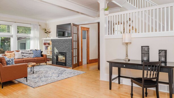 A living room with a fireplace, a sofa, a coffee table, and a dining table with chairs. - Historic Appleton Mansion-Sleeps 13 & Free Parking (Appleton)