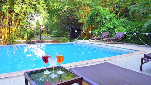 Piscina con lettini e tavolino in vetro con bevande.