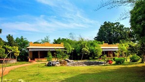 Un bungalow con un vialetto in pietra che conduce all'ingresso, immerso nel verde e alberato.