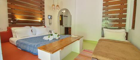 A hotel room with a wooden headboard, a bed with white linens, a wooden desk, and a small table with a brown tablecloth.