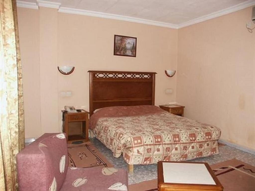 A bedroom with a bed, bedside tables, a nightstand, a chair, and a small table.