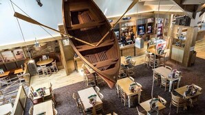 A restaurant with a unique wooden boat structure suspended from the ceiling, surrounded by tables and chairs. - Meadows 33 Hot tub - Southview Holiday Park (Skegness)