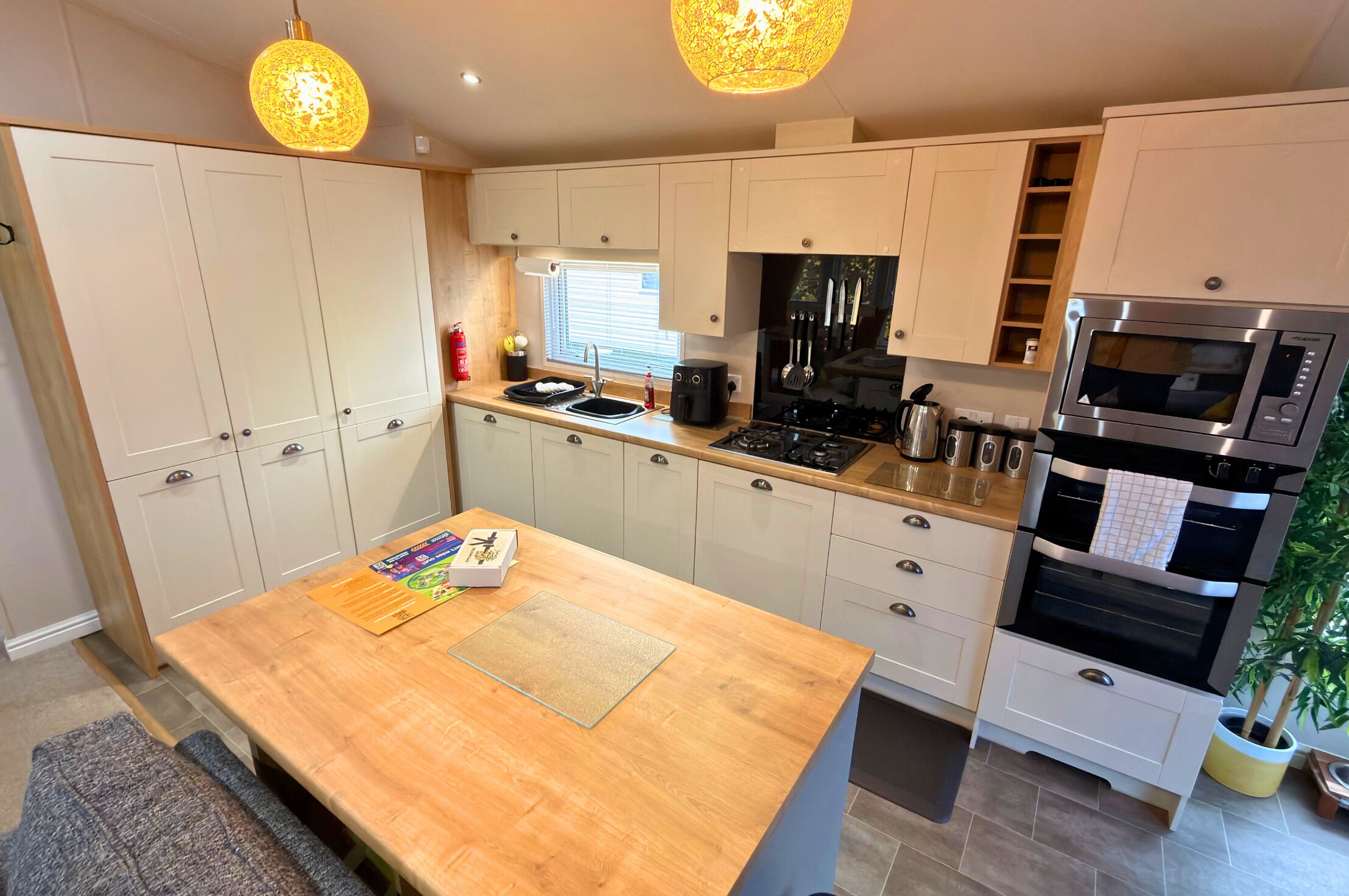 A modern kitchen with white cabinets, a wooden island, stainless steel appliances, and pendant lighting.