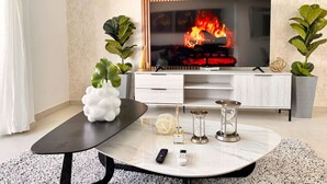 Una sala de estar moderna con un televisor de pantalla plana grande, una mesa de centro de mármol y una chimenea.