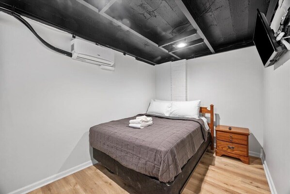 Un dormitorio con cama, mesita de noche de madera y techo con vigas a la vista.