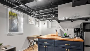 A modern kitchen with dark blue cabinets, a wooden countertop, and a stainless steel refrigerator.