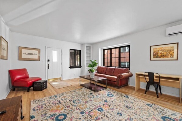 A spacious living room with a red sofa, a coffee table, and a patterned rug.