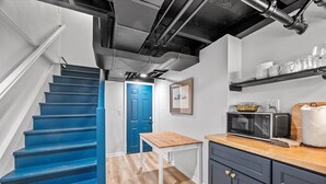 Una cucina con una scala blu, un tavolo di legno e pensili.