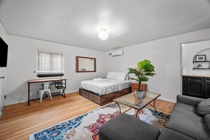 A modern bedroom with a bed, bedside table, and a large window with blinds. - The Walnut Suites - The Hidden Suite (Pittsburgh)