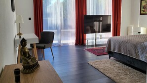 A bedroom with a bed, a TV, a chair, and a statue on a table. - Luxurious apartment in Postira (Postira)