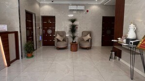 A spacious lobby with a chandelier, two armchairs, a reception desk, and a coffee station. - Sweet Star Serviced Apartments (Tabuk)