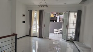 Un'ampia zona giorno con pavimento lucido, ventilatore a soffitto e vista su uno spazio esterno con una bicicletta.