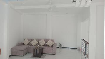Amplia sala de estar con sofá modular, una mesita y una escalera que lleva a un nivel superior.